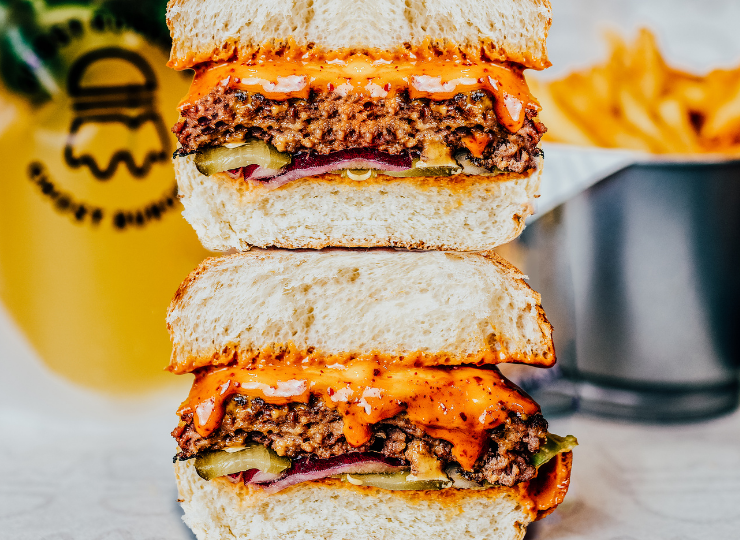 Two beef burgers with sauce and salad in a brioiche bun