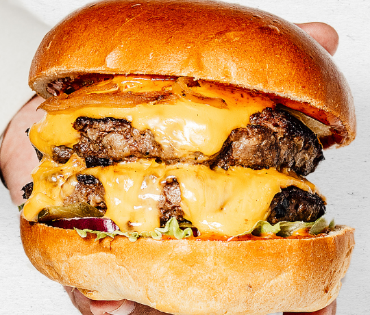 Ghost Burgers serve the best Wagyu Beef Burgers for delivery or takeaway in London Close up of a beef burger filled with melking cheese, sauce and salad